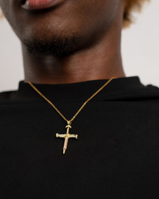 A man wearing a cross necklace with nails depicting the pain of Christ that gave us salvation. He is wearing a black tshirt.
