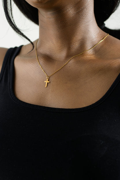 model's neck showing a black tank top with the gold 45cm necklace and a dainty gold cross pendant
