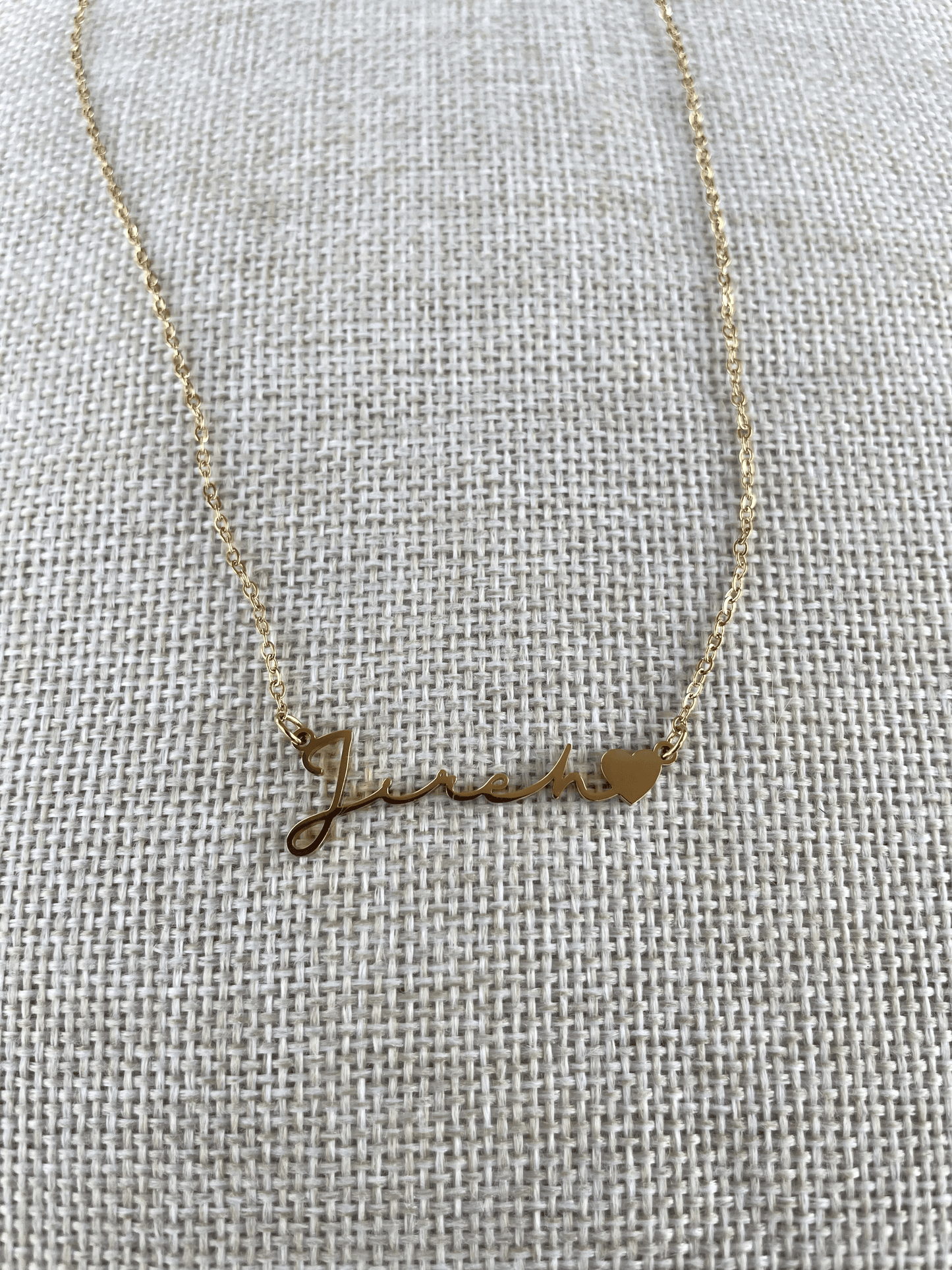 Close-up of Jireh pendant showing text lettering and gold finish