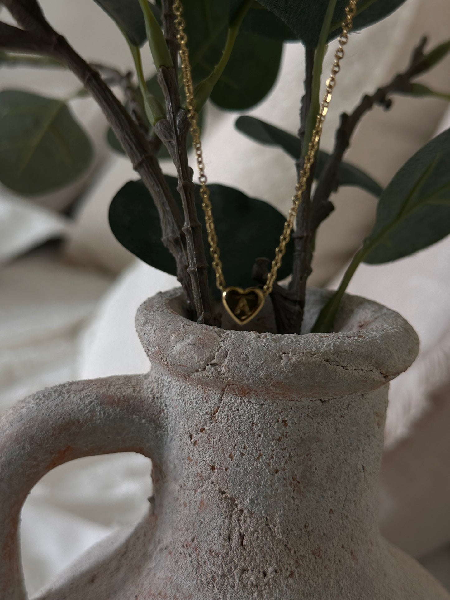 The heart pendant necklace shown against a concrete flower vase.