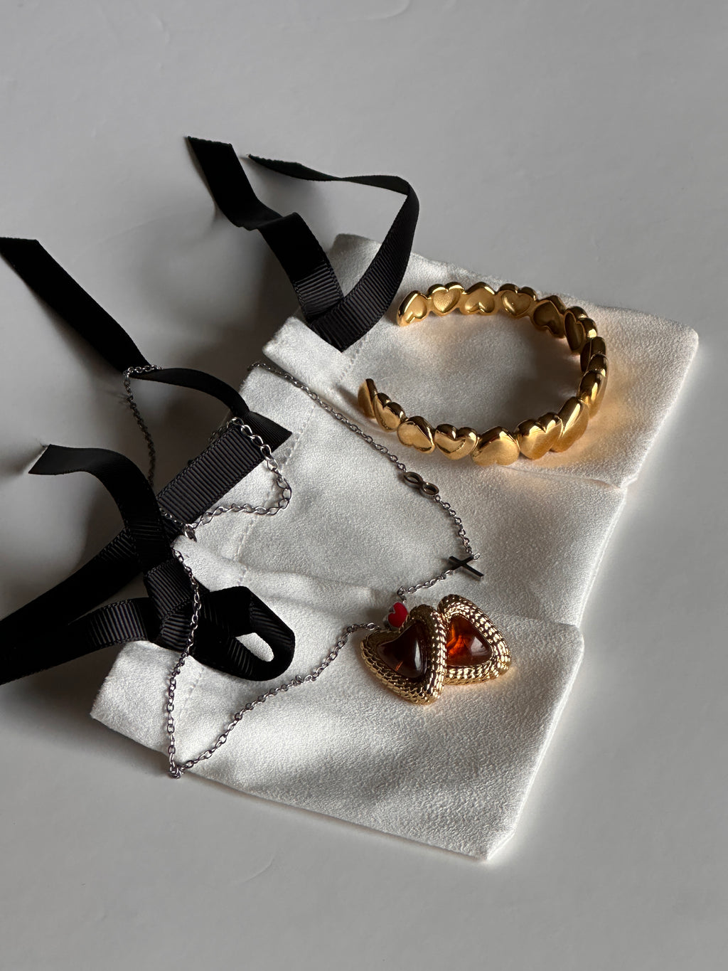 Jewelry set with gold, silver, and black pieces on a white cloth with black ribbons.